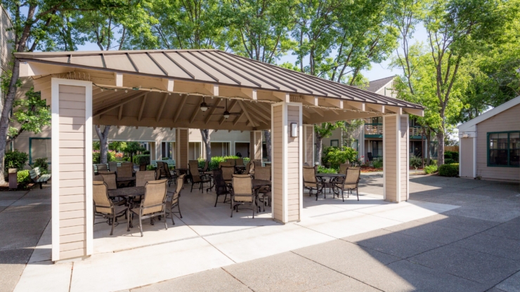 A welcoming outdoor space with shaded seating invites connection and relaxation among lush greenery.