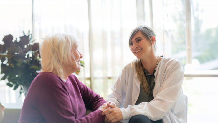 A tender moment between a caregiver and resident, fostering connection in a bright, inviting space.