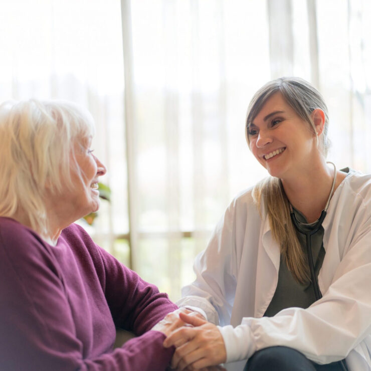 A tender moment between a caregiver and resident, fostering connection in a bright, inviting space.