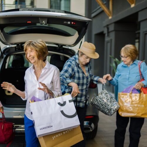 Four cheerful women enjoy a day out, sharing laughter and shopping bags, radiating community spirit.