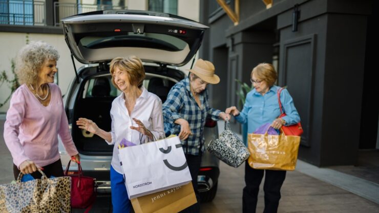 Four cheerful women enjoy a day out, sharing laughter and shopping bags, radiating community spirit.