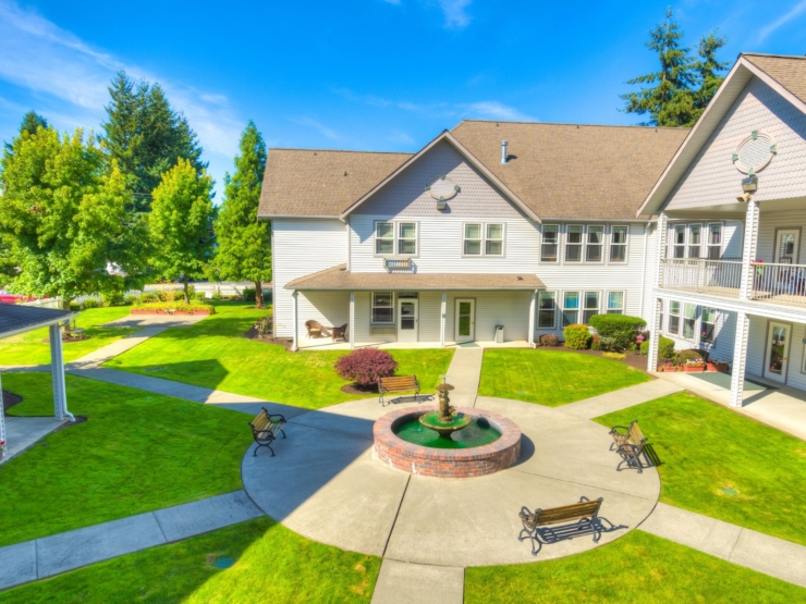 A serene courtyard with lush green lawns, inviting benches, and a gentle fountain fosters community and comfort.