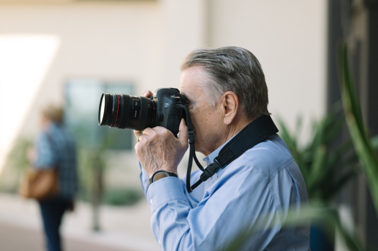 A gentleman captures moments with a camera, embodying creativity and connection in a vibrant community.