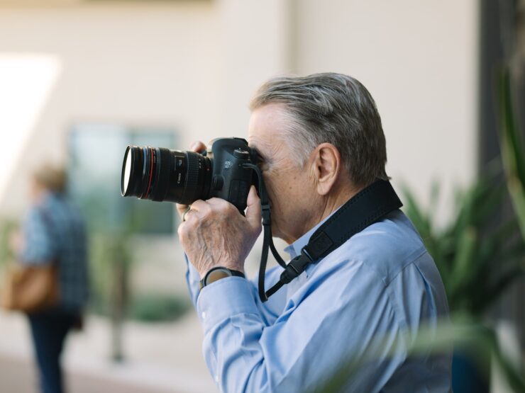 A gentleman captures moments with a camera, embodying creativity and connection in a vibrant community.