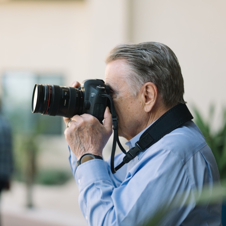 A gentleman captures moments with a camera, embodying creativity and connection in a vibrant community.