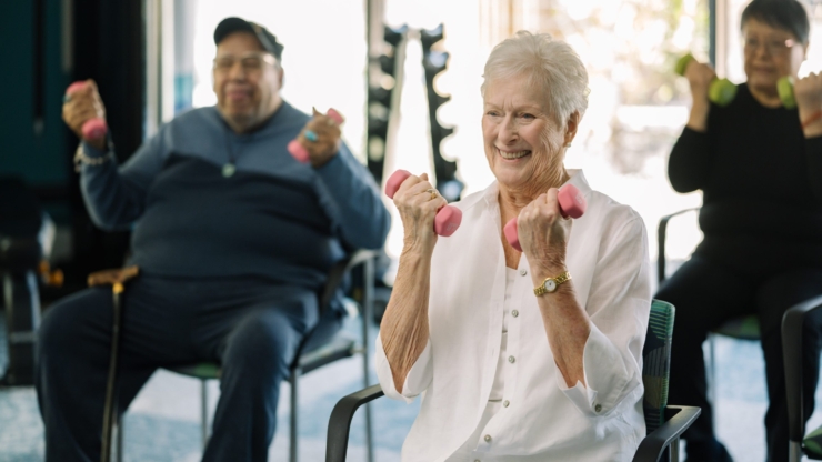 Seniors engage joyfully in a light exercise class, fostering community and wellness in a bright, inviting space.