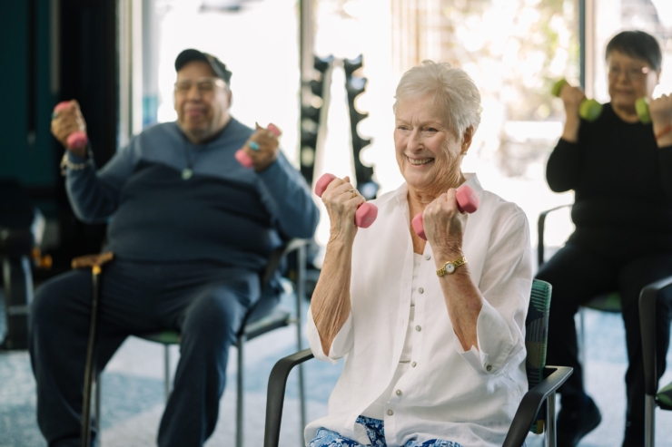 Seniors engage joyfully in a light exercise class, fostering community and wellness in a bright, inviting space.