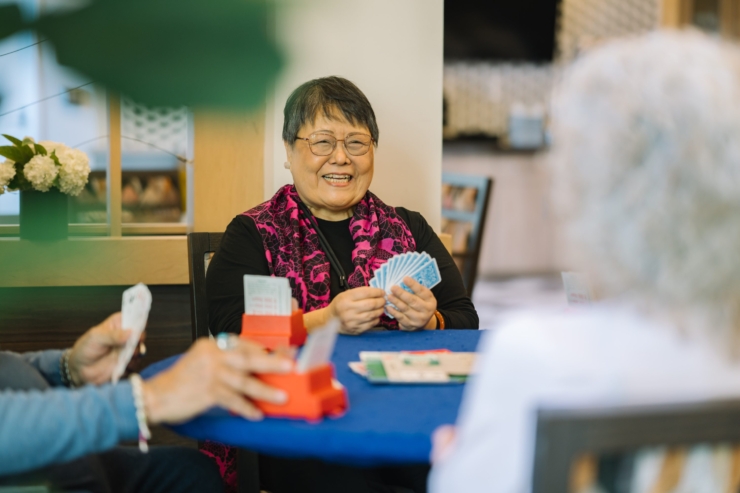 Joyful residents engage in a lively card game, surrounded by a welcoming atmosphere and vibrant decor.