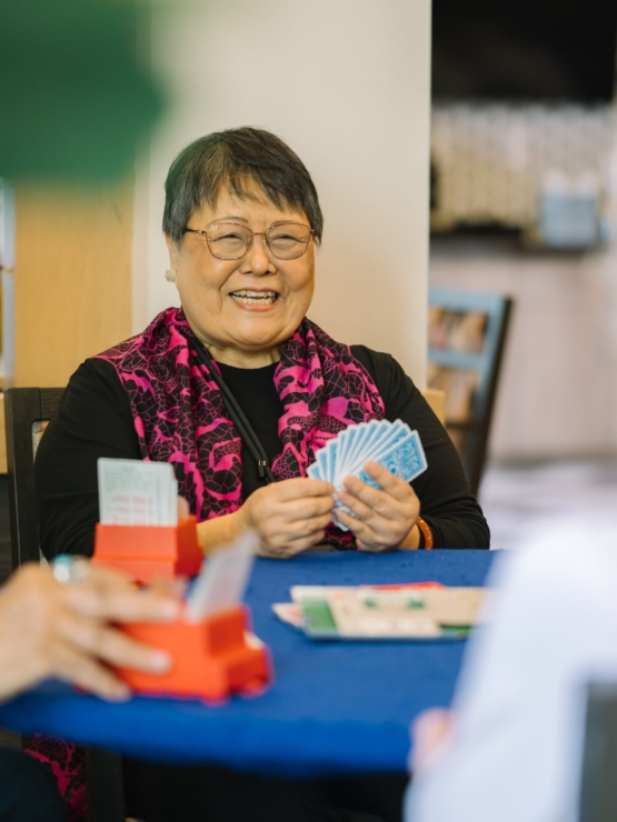 Lively card game among friends, filled with laughter and warmth in a welcoming community space.