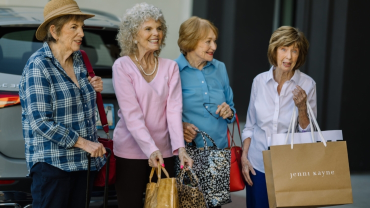 Four cheerful women enjoy a day out, sharing laughter and shopping bags, radiating community spirit.