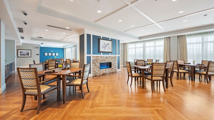 A bright, inviting dining area with warm wood floors, comfortable seating, and cheerful decor, perfect for community gatherings.