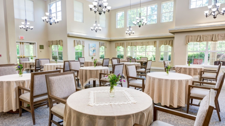 Bright and inviting dining area, featuring elegantly set tables and cheerful floral arrangements, fostering community and warmth.