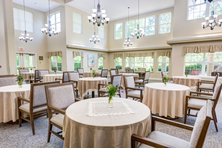 Bright and inviting dining area, featuring elegantly set tables and cheerful floral arrangements, fostering community and warmth.
