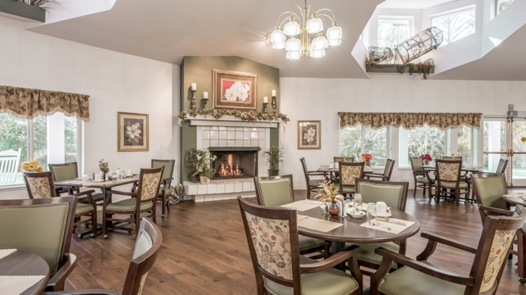 A warm dining area with elegant decor, inviting tables, and a cozy fireplace fosters community and comfort.