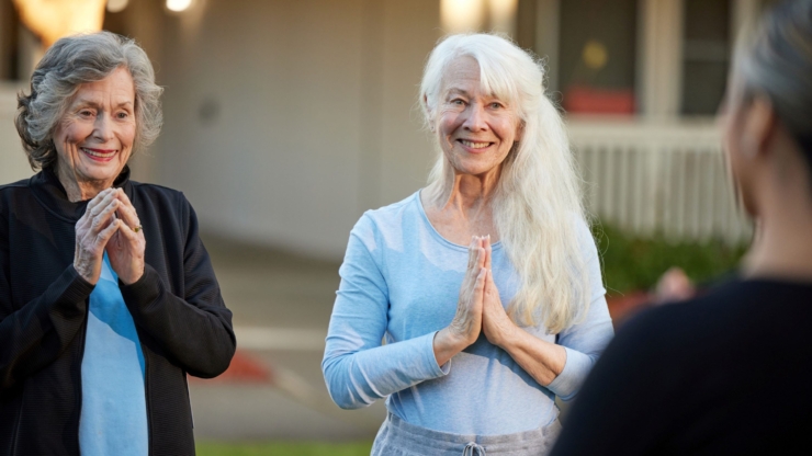 Two smiling women engage warmly outdoors, embodying joy and community spirit in a serene setting.