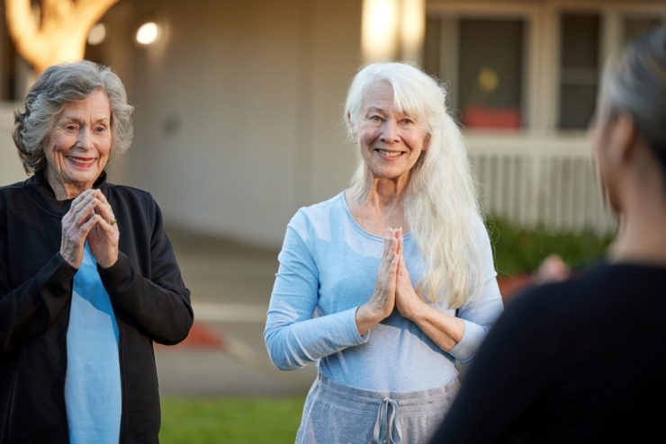 Two smiling women engage warmly outdoors, embodying joy and community spirit in a serene setting.