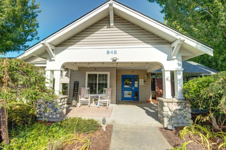 A welcoming porch with rocking chairs invites community and comfort, surrounded by lush greenery.