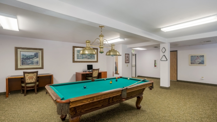 A welcoming activity room features a pool table and cozy seating, fostering community and relaxation.
