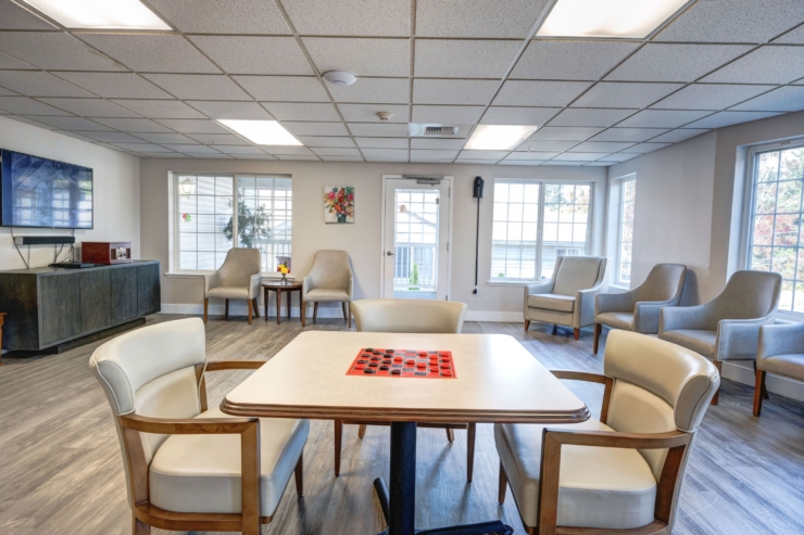 A welcoming lounge filled with natural light, featuring cozy seating and a game table, fosters connection.