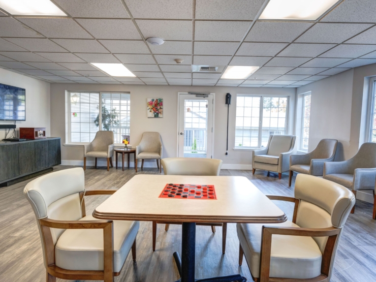 A welcoming lounge filled with natural light, featuring cozy seating and a game table, fosters connection.