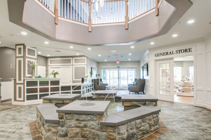 Bright, welcoming lobby with seating, water feature, and nearby general store for resident comfort.