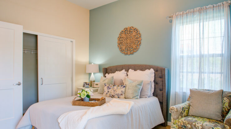 Bright and inviting bedroom featuring comfortable bedding, soft lighting, and a relaxing armchair.