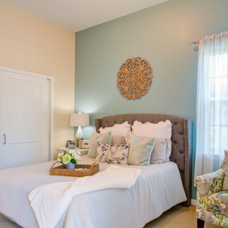 Bright and inviting bedroom featuring comfortable bedding, soft lighting, and a relaxing armchair.