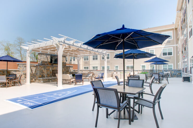 A welcoming outdoor space featuring shuffleboard, cozy seating, and shaded areas for relaxation.