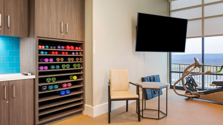 A bright and inviting fitness area, featuring colorful weights, cozy seating, and a view of nature.