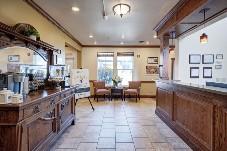 Welcoming reception area with warm lighting, inviting seating, and a coffee station for residents.