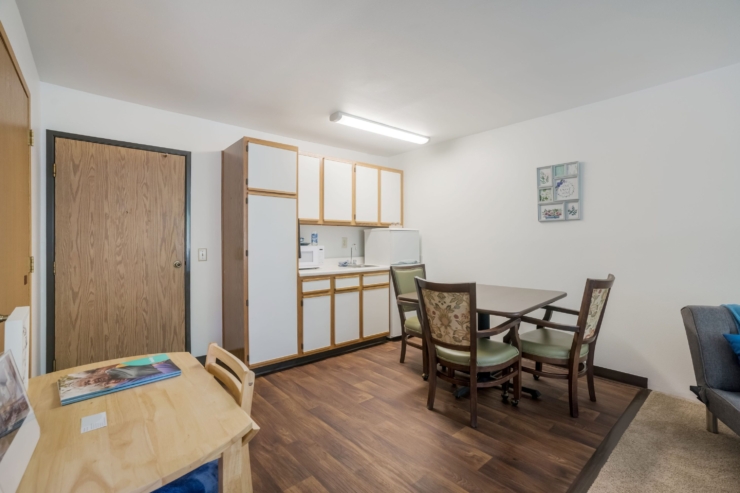 A welcoming space with a dining area, kitchen, and cozy seating invites community and comfort.