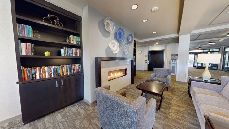 A cozy lounge with soft seating, a warm fireplace, and a welcoming bookshelf, perfect for community gatherings.