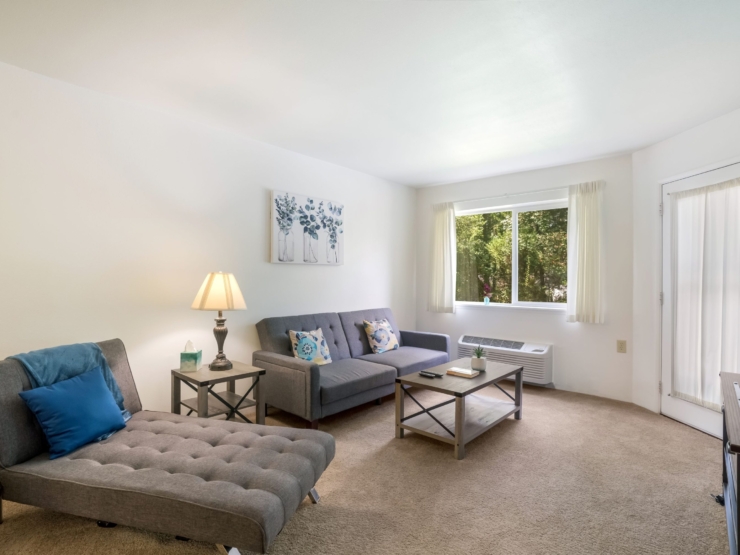 A cozy, sunlit living area invites relaxation, featuring comfortable seating and warm decor.