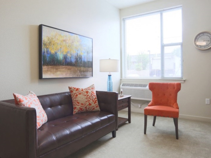 A bright, inviting space featuring a stylish couch, cheerful chair, and artwork, perfect for relaxation.