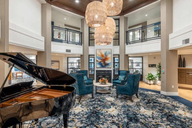 A beautifully designed community space featuring a grand piano, inviting seating, and vibrant artwork, promoting warmth and connection.