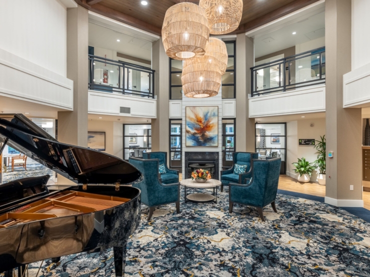 A beautifully designed community space featuring a grand piano, inviting seating, and vibrant artwork, promoting warmth and connection.