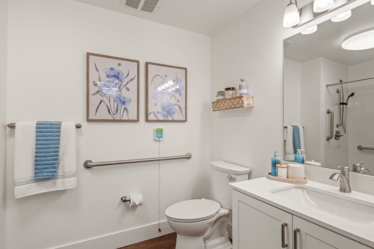 Bright and inviting, this bathroom features soothing floral artwork, soft towels, and accessible amenities for a comfortable environment.