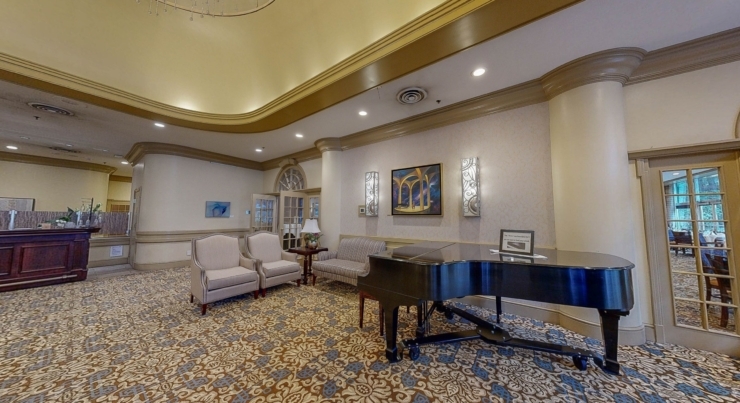 A welcoming lobby features comfortable seating, a grand piano, and warm decor, inviting community and connection.