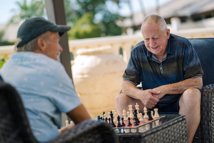 Two friends enjoy a friendly chess match outdoors, fostering connection and engagement in a serene setting.