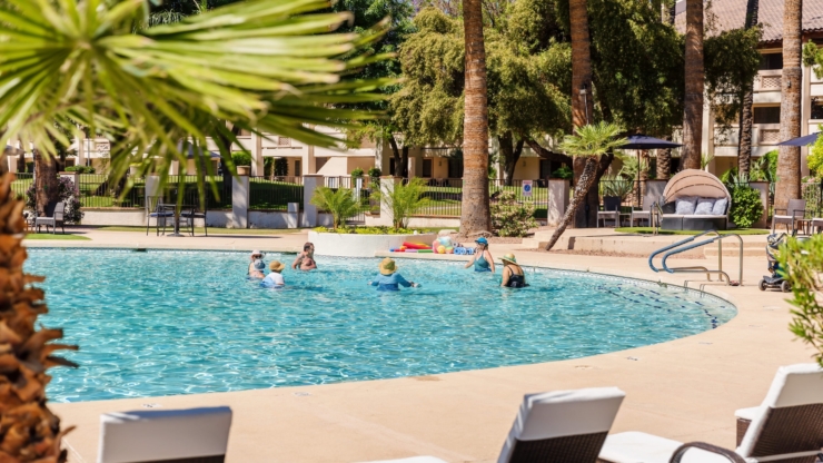 Residents enjoy a refreshing swim in a vibrant, sunlit pool surrounded by lush greenery, fostering community and joy.