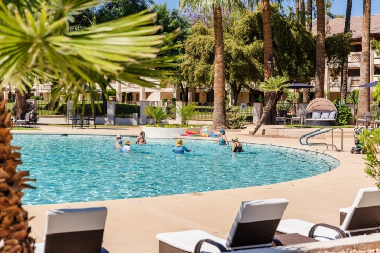 Residents enjoy a refreshing swim in a vibrant, sunlit pool surrounded by lush greenery, fostering community and joy.