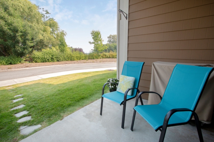 A welcoming porch with vibrant chairs invites relaxation, surrounded by lush greenery and a peaceful view.