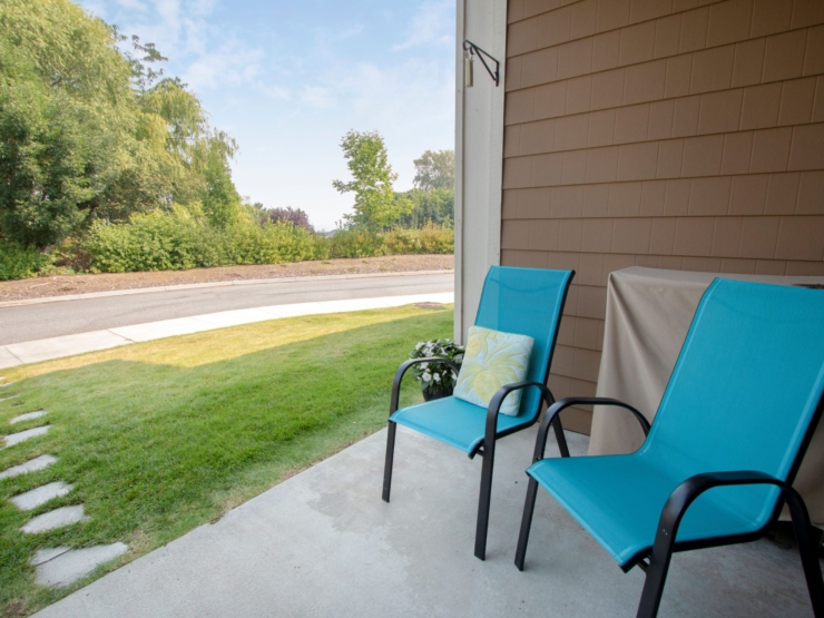 A welcoming porch with vibrant chairs invites relaxation, surrounded by lush greenery and a peaceful view.