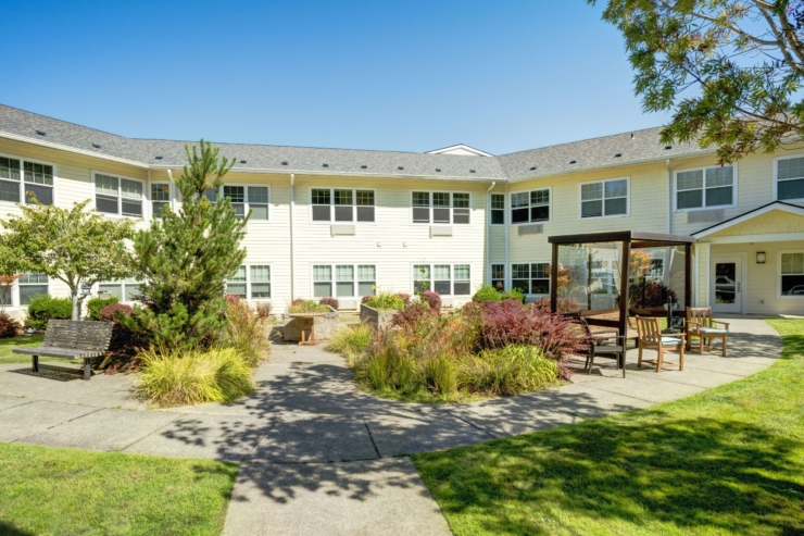 A serene courtyard invites relaxation, featuring cozy seating among vibrant greenery and flowers.