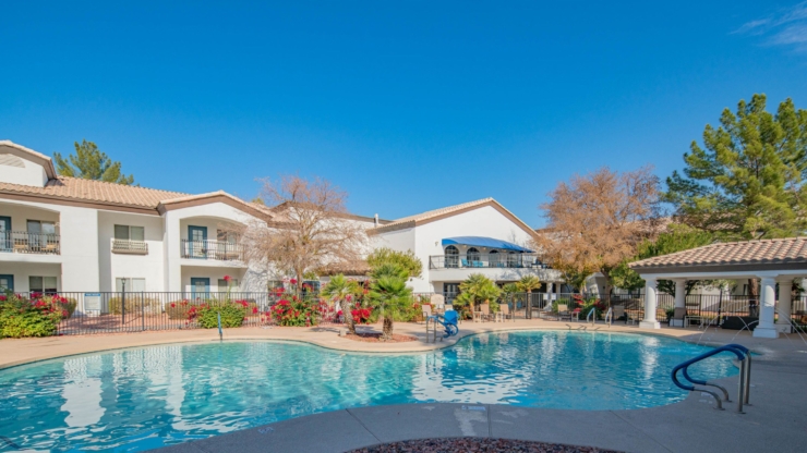 A serene poolside oasis invites relaxation, surrounded by vibrant flowers and welcoming community spaces.
