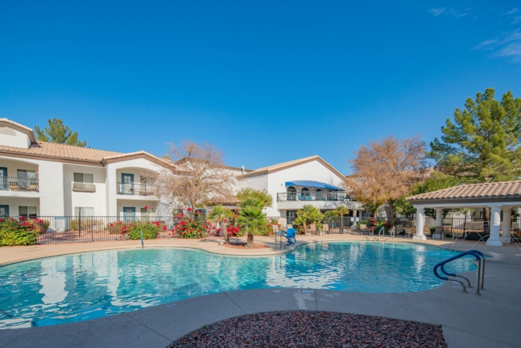 A serene poolside oasis invites relaxation, surrounded by vibrant flowers and welcoming community spaces.