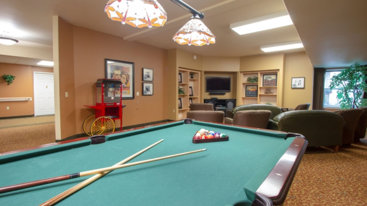 A welcoming community space with a billiard table, cozy seating, and bright, cheerful decor.
