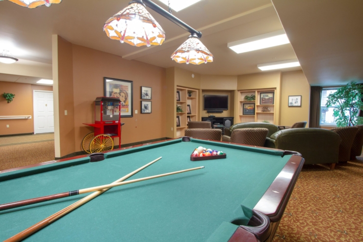 A welcoming community space with a billiard table, cozy seating, and bright, cheerful decor.