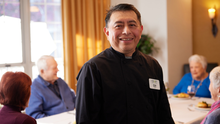 A cheerful chef engages warmly with residents, creating a welcoming and vibrant dining atmosphere.