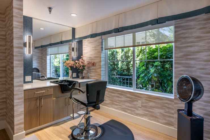A welcoming salon space, filled with natural light, features comfortable seating and vibrant decor, perfect for community connections.